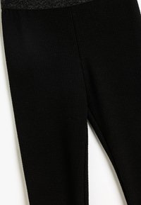 Leggings noirs à côtes avec une surface texturée, présentant une coupe ajustée et une taille élastique pour un confort et une flexibilité optimaux.