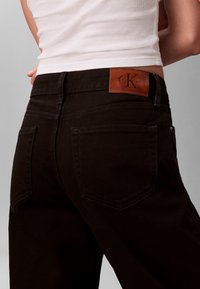 Zwarte denim jeans met een leren logo-label bij de taille. Het ontwerp bevat twee achterzakken met zichtbare stikdetails.