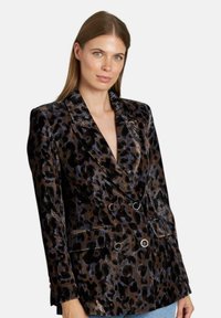 Blazer doppiopetto in stampa leopardo, caratterizzato da una texture in velluto lucido, vestibilità su misura, revers a punta e due tasche frontali.