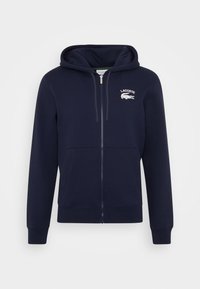Námořnicky modrá mikina na zip z bavlněné směsi, s přední kapsou, žebrovanými manžetami a vyšitým logem Lacoste na hrudi.