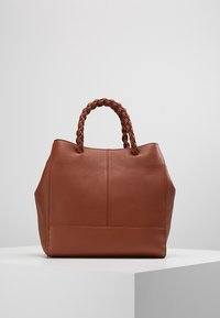 Bruine leren handtas met een gevlochten handvat, gestructureerde vorm, zichtbare naden en een gladde textuur. Beschikt over een eigentijdse minimalistische uitstraling.