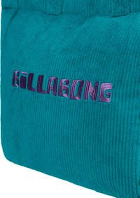 Turquoise corduroy fabric with vertical ribbing, featuring purple embroidered "Billabong" logo, soft texture and distinct design.