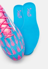Jasnoniebieskie buty piłkarskie z różowymi akcentami i kanciastymi wzorami. Zawierają dopasowaną niebieską wkładkę z brandingiem "F50".