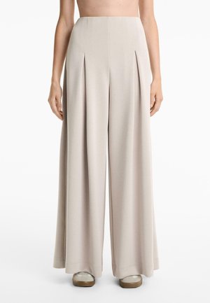 Beige weite Hose aus weichem Stoff, mit vorderen Falten und einem sauberen Abschluss am Saum. Einfaches, zeitgenössisches Design.