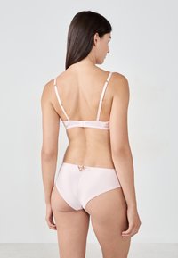 Ensemble en rose clair comprenant un soutien-gorge et une culotte hipster en tissu doux. Le soutien-gorge possède des bretelles ajustables et une fermeture à crochets ; la culotte présente un détail découpé décoratif.
