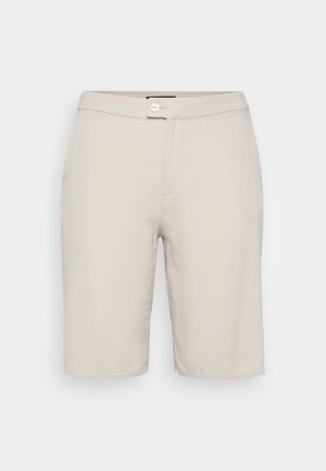 Shorts en coton beige avec fermeture à bouton, deux poches latérales et coupe droite. Présente une texture lisse et un design simple.