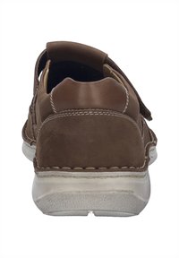 Bruine leren schoen met een ronde achterkant, gestikte details, een gevoerde kraag en een witte rubberen zool. Open achterkant ontwerp voor gemakkelijk aan- en uittrekken.
