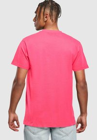 Camiseta de algodón de manga corta y cuello redondo en un brillante color rosa. Presenta un corte relajado con dobladillo recto y detalles de costura mínimos.