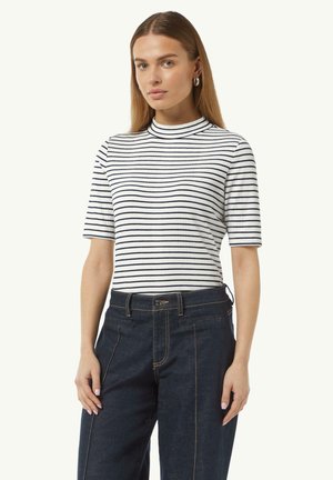 Wit en marineblauw gestreepte kortemouwen top met een hoge kraag; zachte, geribbelde textuur; gedragen met donkerblauwe, op maat gemaakte denim broek.
