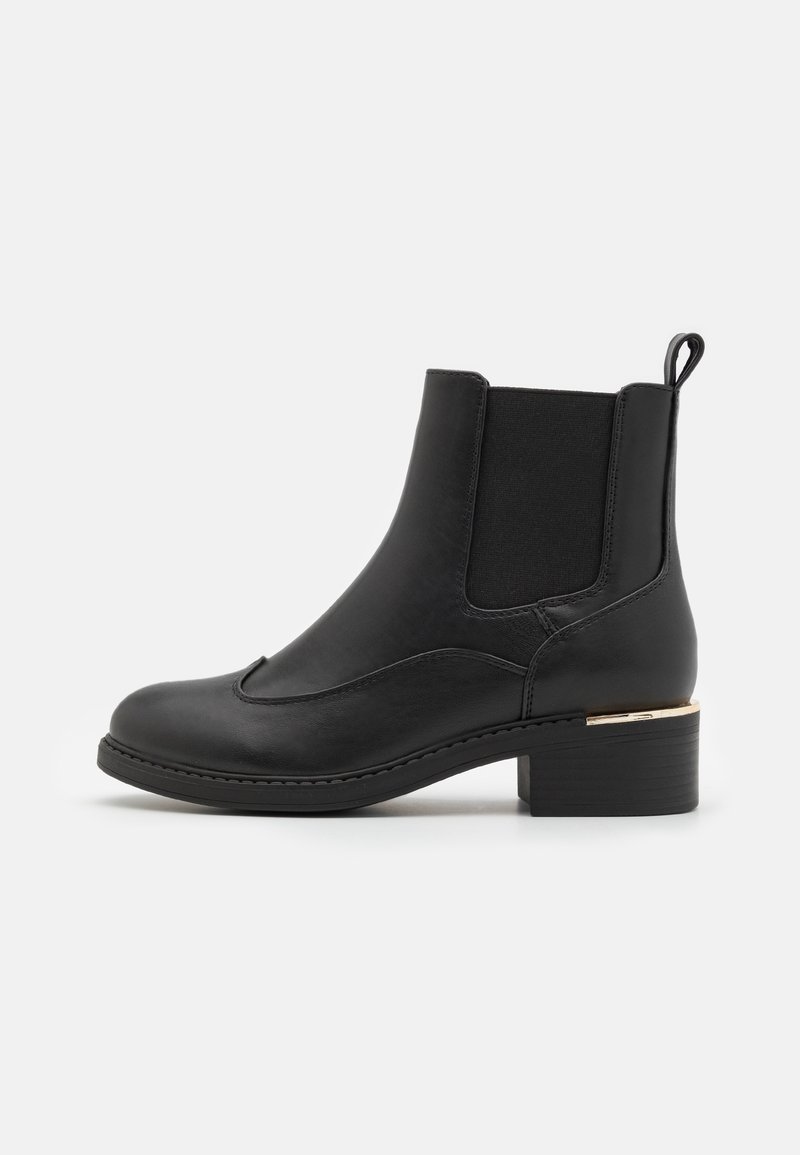 Bottine en cuir noir avec panneau latéral élastique, languette à l'arrière, petit talon superposé et accent doré près du talon.