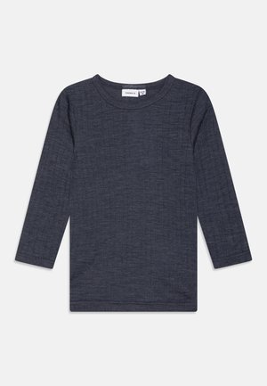 Camisa gris de manga larga hecha de tela texturizada, con cuello redondo y corte recto, con detalles de costura mínimos a lo largo de los dobladillos.