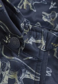 Marint tyg med dinosaurmönster, med synlig knapp och sömnadsdetaljer. Materialet ser slätt ut med en lätt glans.