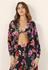 Bikiny s květinovým potiskem na černém pozadí, zdobené živými růžovými, fialovými a červenými květy. Doplněné o košili na knoflíky ve stejném provedení.