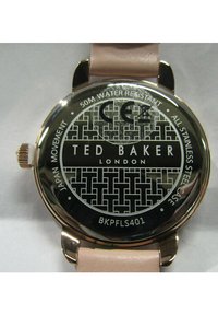 Esfera de reloj redonda de acero inoxidable con un dial negro estampado, acentos dorados y una correa de cuero rosa claro. Resistente al agua hasta 50 metros.