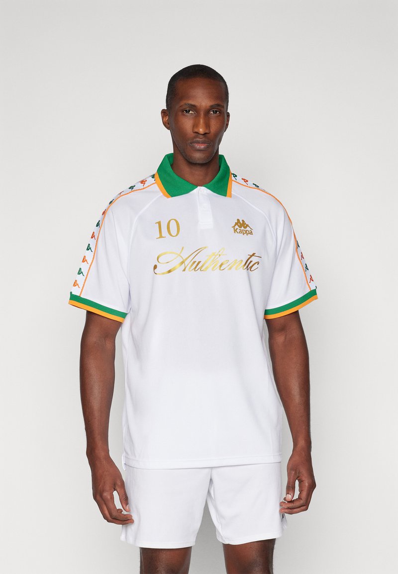 T-shirt polo blanc avec col vert et accents orange. Monte un texte doré "Authentique" et le numéro "10". Patron à rayures sur les manches.