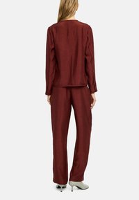 Bordowy dwuczęściowy strój z teksturowanej tkaniny; góra z długimi rękawami, spodnie o szerokich nogawkach, zestawione z butami na obcasie w kolorze mięty.