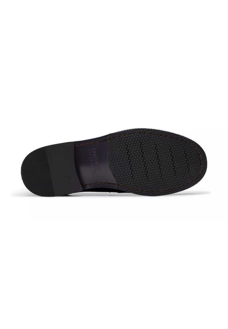 Semelle de chaussure noire avec motif de grip hexagonal, surface lisse, bout arrondi et talon légèrement surélevé. Détail de couture visible le long du bord.