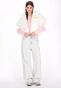 Iryzująca krótka kamizelka puchowa z imitacją futra, zestawiona z różowym topem z długim rękawem i jasnoniebieskimi szerokimi dżinsami oraz srebrnymi trampkami.