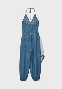 Combinaison en denim avec col licou en V, taille et poignets élastiques, poches arrière, et détail en tissu rayé sur le côté droit.