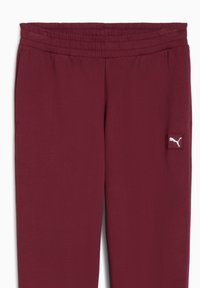 Mørkerøde træningsbukser med elastisk talje, sidelommer og et lille hvidt Puma-logo på nederste venstre ben. Glat tekstur.