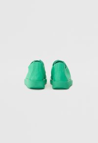 Adidași verzi cu un superior din piele texturată, tocul rotunjit și o talpă din cauciuc asortată. Prezintă detalii de cusătură pe partea din spate.