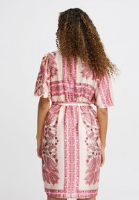 Rochie roz fluidă cu modele florale și paisley, mâneci scurte și o curea legată la talie; material neted și design până la genunchi.