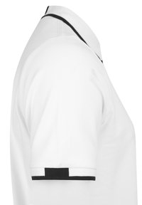 Camisa polo blanca con una tela texturizada. Presenta un cuello clásico con un ribete negro y detalles de rayas en blanco y negro en las mangas.