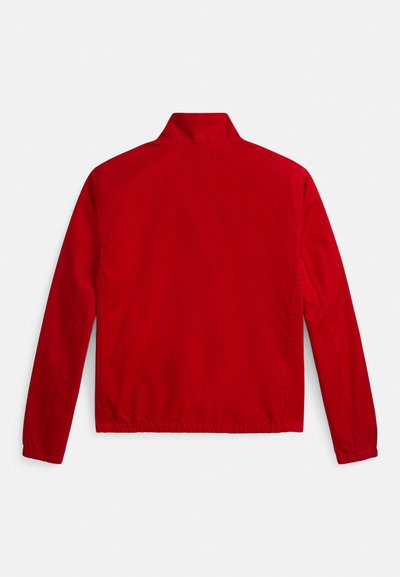 Piros dzseki álló gallérral, elasztikus mandzsettákkal és sima anyagfelülettel; egyszerű, díszítés nélküli hátrésszel tervezve.