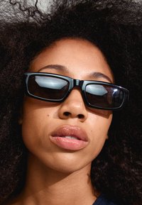 Black rectangular sunglasses with dark lenses. Thick plastic frames feature rounded edges. Smooth surface, reflecting light.