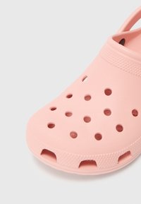 Pink slip-on clog featuring a lightweight, perforated design, smooth texture, and rounded toe with drainage holes and a back strap.