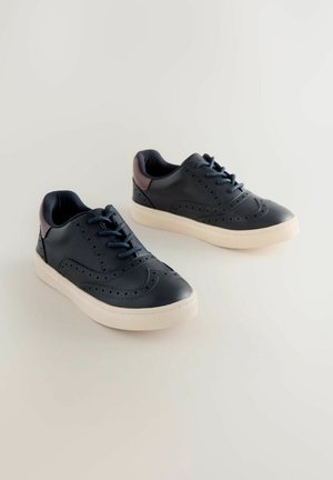 Baskets en cuir marine avec un design perforé, semelle en caoutchouc beige et accents marron foncé au talon. Comprend des lacets ronds et un col rembourré.