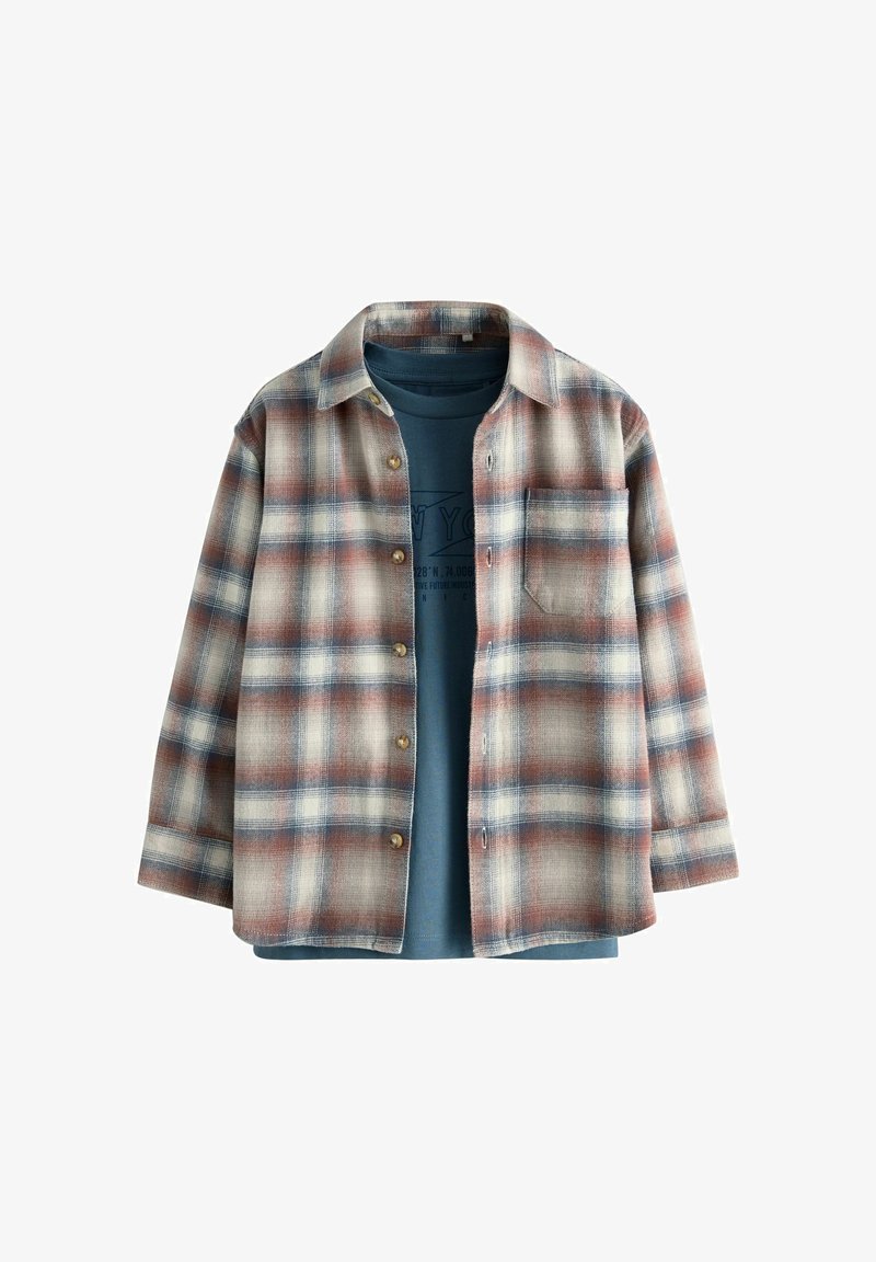 Cămașă din flanel cu un model în carouri bej, albastru și ruginie, cu închidere prin butoane, mâneci lungi și un buzunar pe piept deasupra unei tricouri albastre.
