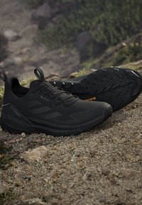 Scarpe da trail running Adidas Terrex nere con suole in gomma Continental robuste su terreno roccioso all'aperto.