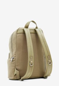 Khaki batoh s dvojitou texturou, hladkými koženými popruhy a stříbrným kováním. Vybaven zipovou kapsou a polstrovanými zády pro pohodlí.