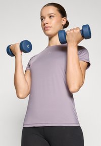 Purple athletic t-shirt with short sleeves, rounded neckline, slim fit, made of smooth fabric; holding blue dumbbells with a weight of 3 kg.