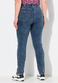 Siniseen denimkangasta valmistetut korkeat farkut, joissa on joustava vyötärö, takataskut ja hieman haalistunut pinta.