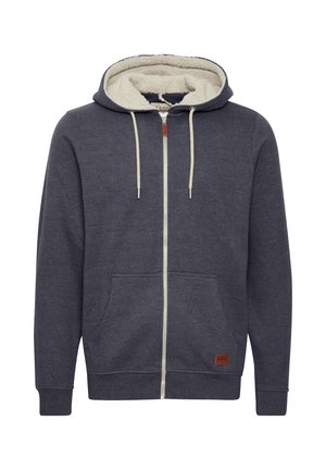 Felpa con cappuccio grigio scuro, dotata di zip, foderata in morbido pile color crema, con tasche frontali e una patch in pelle sul lato sinistro in basso. Presenta dei lacci.