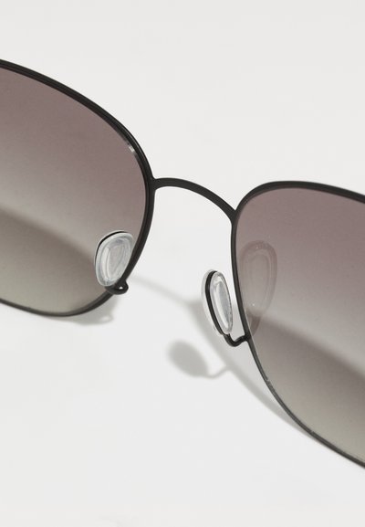 Black metal sunglasses with gradient tinted lenses. Features nose pads for comfort and slender frame design, displaying a sleek aesthetic.