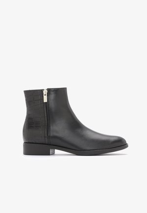 Bottine en cuir noir avec fermeture éclair latérale et motif crocodile texturé sur le talon, talon bas et bout arrondi.