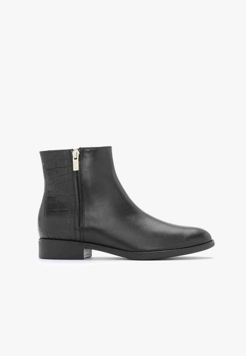 Bottine en cuir noir avec fermeture éclair latérale et motif crocodile texturé sur le talon, talon bas et bout arrondi.