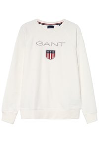 Bílý svetr s dlouhým rukávem s textem "GANT" a štítovým logem se třemi hvězdami nad červenými a bílými vertikálními pruhy.
