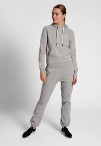 Grijze hoodie met trekkoorden en een kangoeroezak, gecombineerd met bijpassende sweatpants. Gemaakt van zacht materiaal, voorzien van geribde manchetten en tailleband.