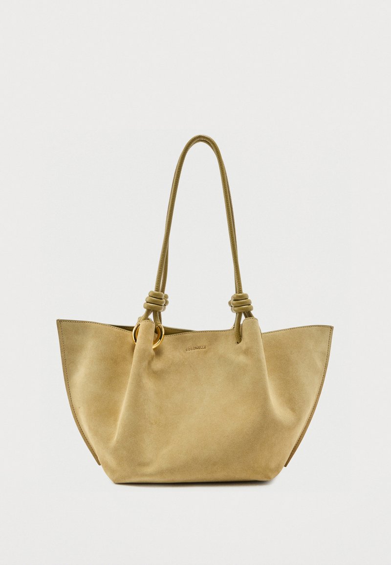 Μπεζ τσάντα tote από σουέτ με μακριές λαβές από δεμένες σχοινί και λεπτομέρεια με χρυσό κρίκο, διαθέτοντας ευρύχωρο, φαρδύ σχεδιασμό.