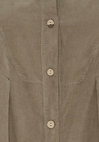 Brun kordfløjlsskjorte med lodret ribbning, der har træknapper og en knappet front. Skræddersyet design med svage syningsdetaljer.