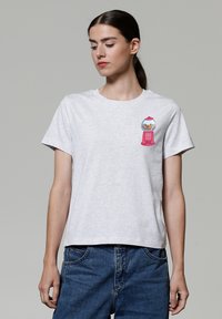 Grau Baumwoll-T-Shirt mit einem bunten Kaugummiautomaten-Design auf der linken Brust. Kurze Ärmel und ein klassischer runder Ausschnitt.