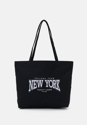 Musta kangaskassi pitkillä kahvoilla, jossa valkoista ja harmaata tekstiä: "College Team New York Varsity League Est. 2001" edessä.