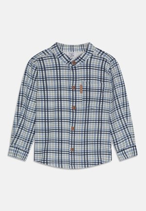 Koszula na guziki z długim rękawem w niebiesko-biało-beżową kratę oraz kieszenią na piersi z małą brązową metką.