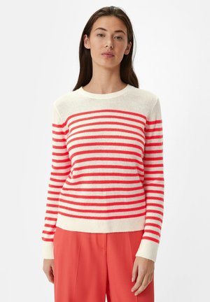 Gestreepte trui in crème met dikke koraalkleurige strepen. Zachte textuur, ronde halslijn, aansluitende manchetten en zoom. Gecombineerd met koraalkleurige broek.