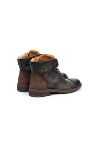 Botas de tobillo de cuero marrón y verde con un acabado texturizado, puntera redonda y cordones. Presentan un tacón de madera y un forro interior en tono marrón.