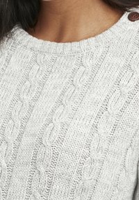 Pull gris clair tricoté avec un motif torsadé, col rond et deux boutons en bois sur l'épaule. Tissu texturé et confortable.